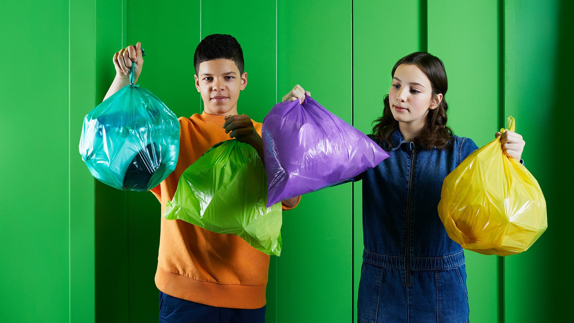 2 Kinder, die die Arme voller Plastikmüll haben