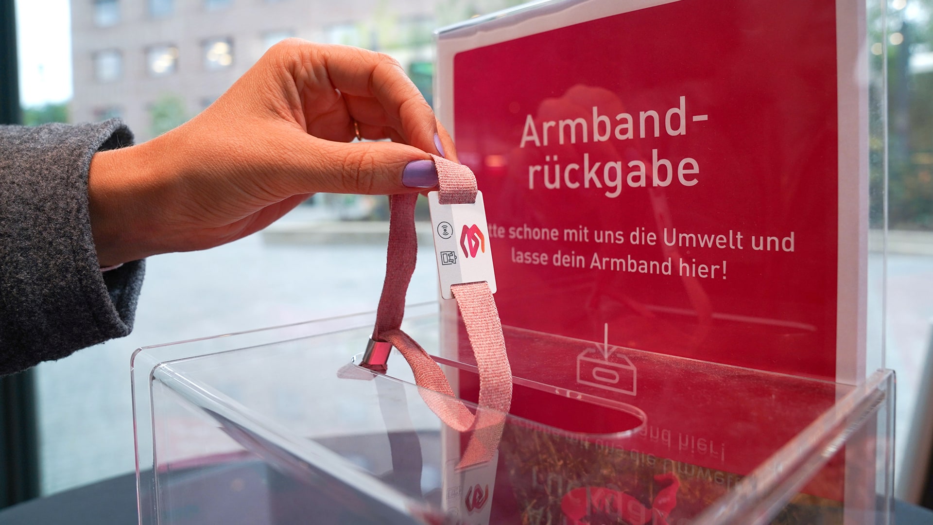 Hand, die ein Ticket-Armband in den Armbandrückgabe-Behälter einwirft